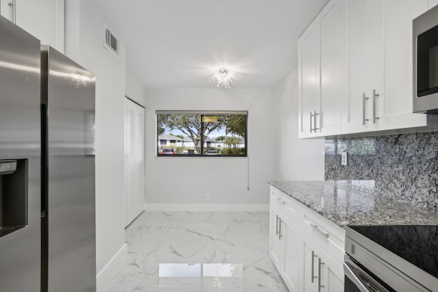 kitchen featuring tasteful backsplash, white cabinetry, light stone countertops, and appliances with stainless steel finishes