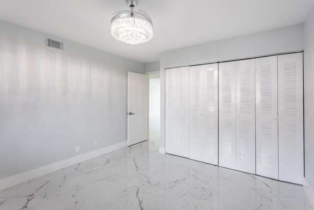 unfurnished bedroom featuring a notable chandelier and a closet