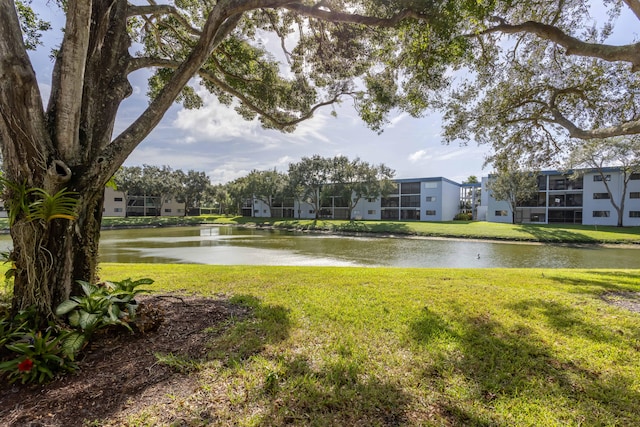 view of property's community with a lawn and a water view