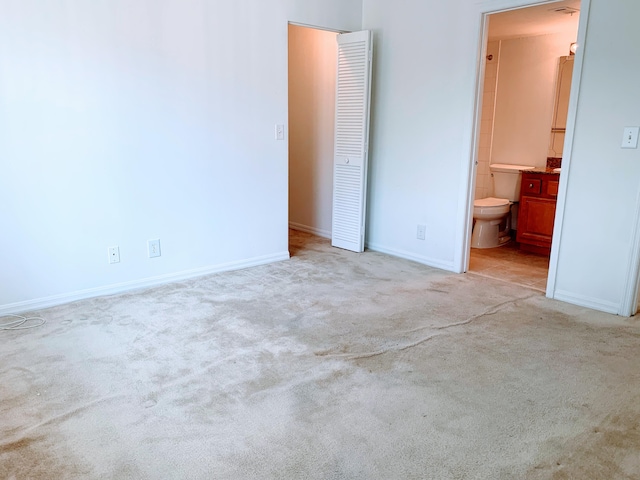 unfurnished bedroom featuring light carpet and connected bathroom