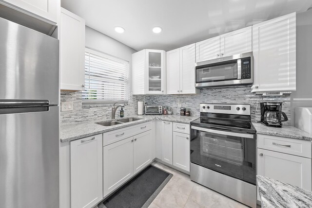 kitchen with sink, appliances with stainless steel finishes, white cabinetry, and light stone countertops