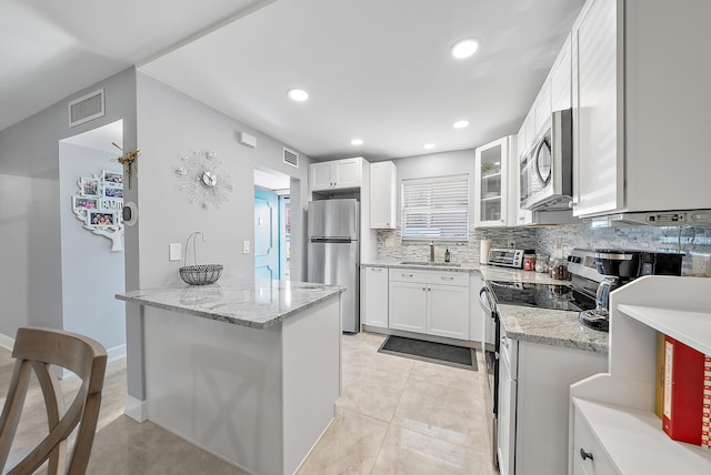 kitchen with tasteful backsplash, light stone counters, stainless steel appliances, sink, and white cabinets