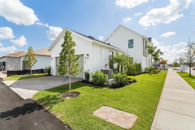 950 SW Prairie Ave, Palm City, FL 34990 - view of home's exterior featuring board and batten siding, a garage, a lawn, driveway, and cooling unit