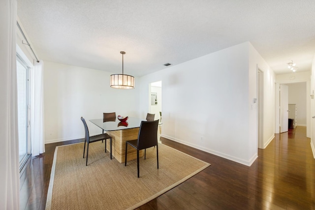 dining area featuring dark hardwood / wood-style flooring and a textured ceiling