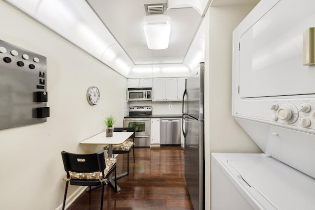 clothes washing area featuring dark hardwood / wood-style flooring and stacked washer and dryer