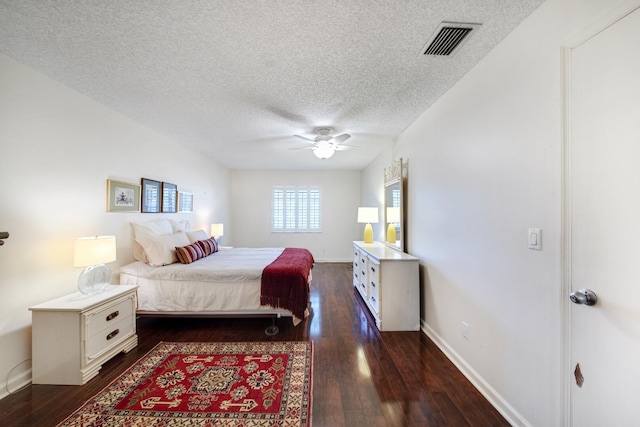 bedroom with a textured ceiling, dark wood-type flooring, and ceiling fan