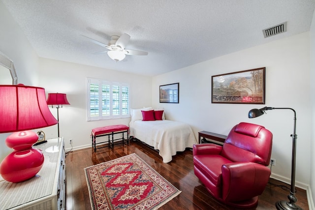 bedroom featuring dark wood-type flooring, a textured ceiling, and ceiling fan