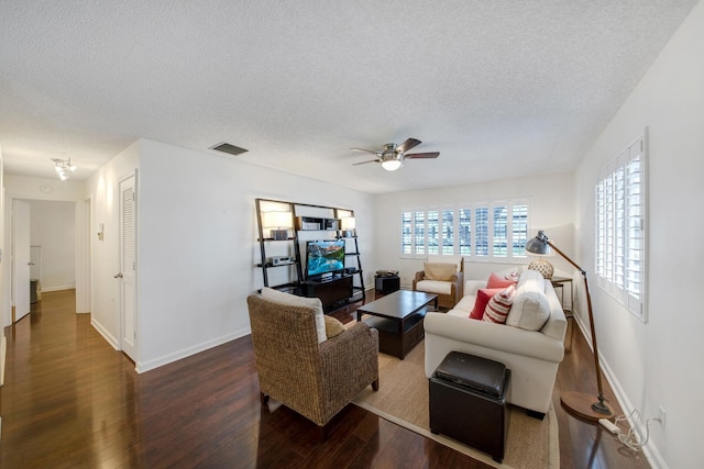 living room with ceiling fan, dark wood-type flooring, and a textured ceiling