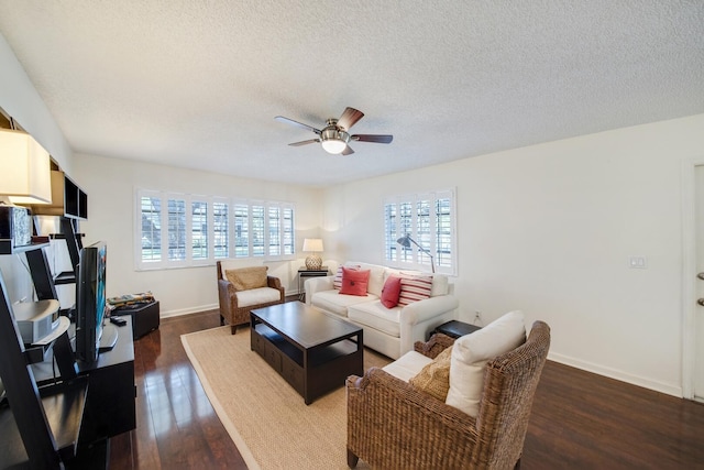 living room with ceiling fan, plenty of natural light, dark wood-type flooring, and a textured ceiling