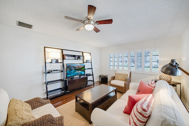 living room with ceiling fan, hardwood / wood-style floors, and a textured ceiling