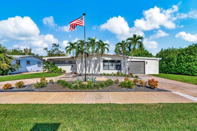 mid-century modern home with driveway, a garage, a front yard, and stucco siding