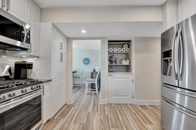 kitchen with appliances with stainless steel finishes, white cabinetry, recessed lighting, light wood-style floors, and backsplash
