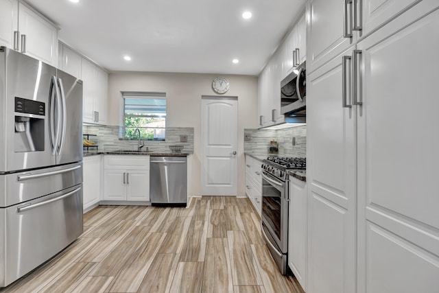 kitchen featuring light hardwood / wood-style flooring, sink, backsplash, white cabinetry, and appliances with stainless steel finishes