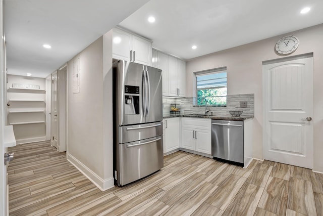 kitchen with appliances with stainless steel finishes, a sink, dark stone counters, white cabinetry, and recessed lighting