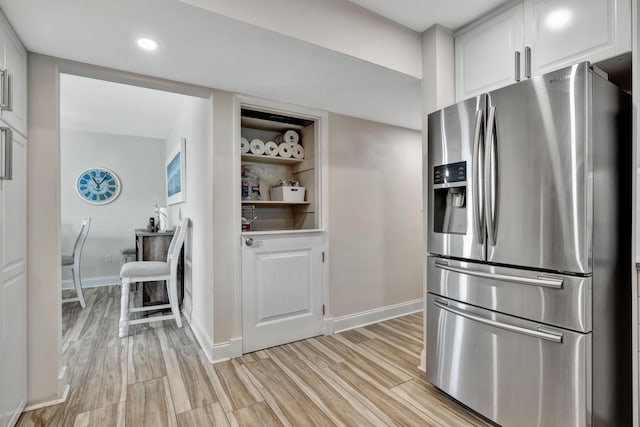 kitchen featuring stainless steel fridge with ice dispenser, white cabinets, light wood finished floors, baseboards, and recessed lighting