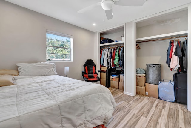 bedroom featuring light wood-type flooring, ceiling fan, and two closets