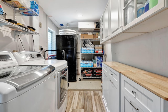 laundry room with separate washer and dryer, light wood finished floors, and cabinet space