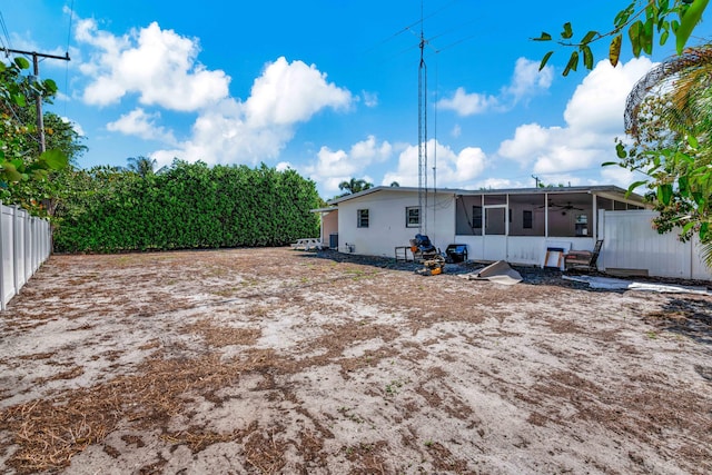 back of property featuring ceiling fan, a fenced backyard, and a sunroom