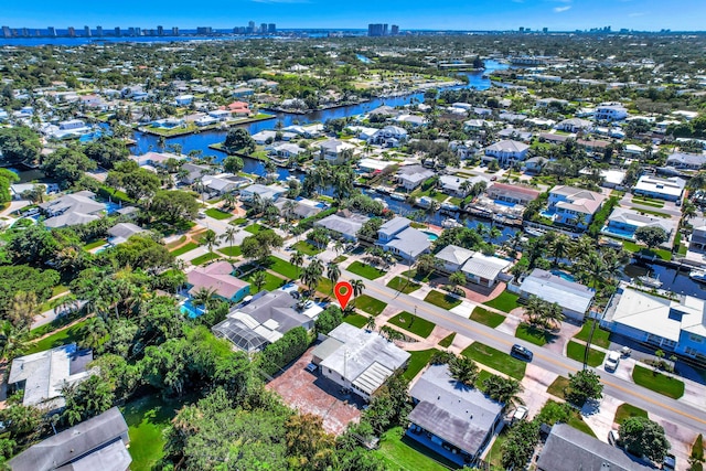 aerial view of property and surrounding area with a skyline view, a large body of water, and nearby suburban area