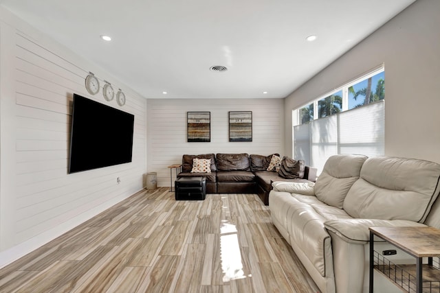 living area featuring wooden walls, light wood-type flooring, and recessed lighting