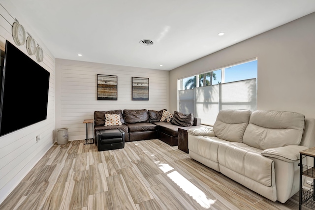 living area with wood walls, light wood-style flooring, and recessed lighting