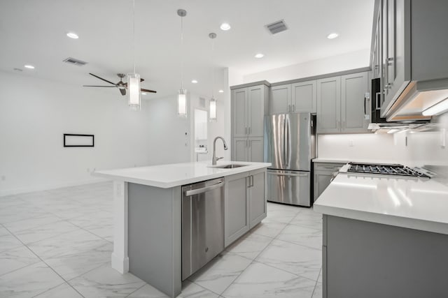 kitchen with gray cabinets, decorative light fixtures, sink, stainless steel appliances, and a center island with sink