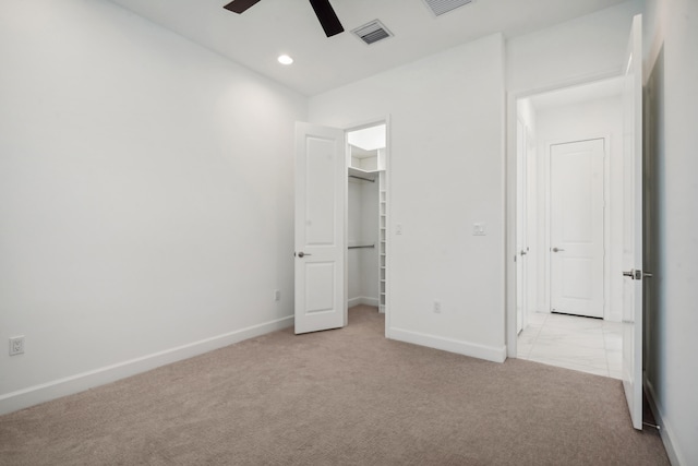 unfurnished bedroom featuring a spacious closet, light carpet, ceiling fan, and a closet