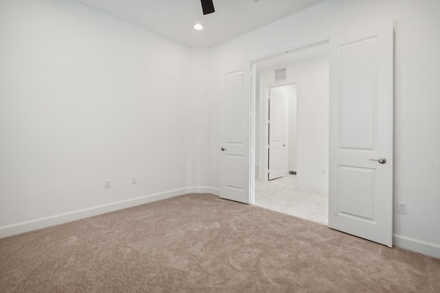 spare room with ceiling fan and light colored carpet