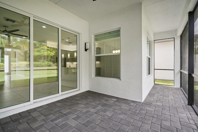 unfurnished sunroom with ceiling fan