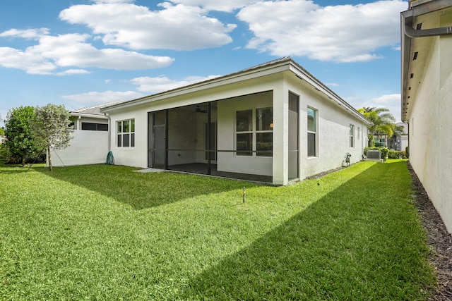 rear view of property with a sunroom, a yard, and central AC unit