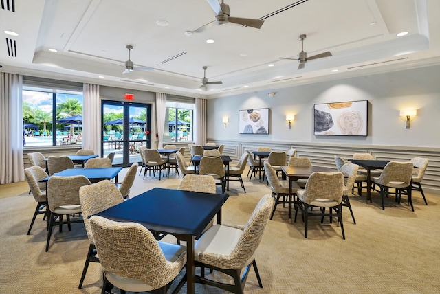 carpeted dining room with ornamental molding, french doors, a wealth of natural light, and a raised ceiling