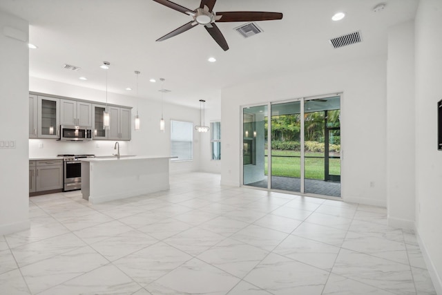 unfurnished living room featuring a wealth of natural light, sink, and ceiling fan