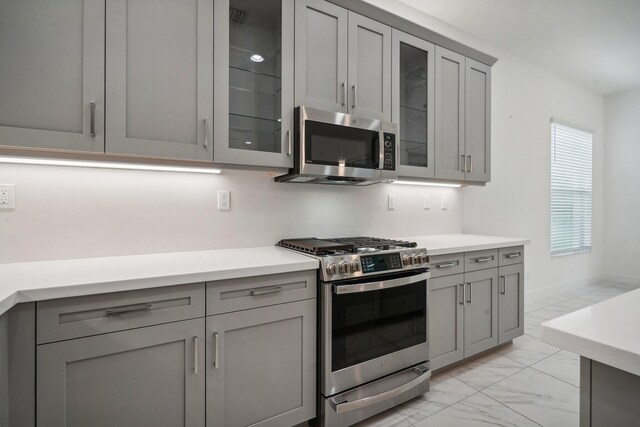 kitchen with hanging light fixtures, gray cabinetry, and appliances with stainless steel finishes