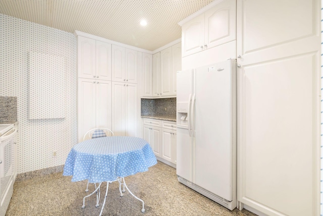 kitchen featuring white cabinetry and white refrigerator with ice dispenser