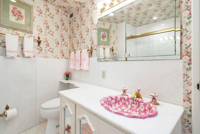 bathroom with a shower with shower door, vanity, and toilet