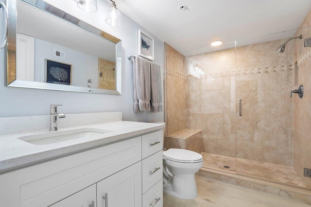 bathroom featuring toilet, vanity, and a shower with door