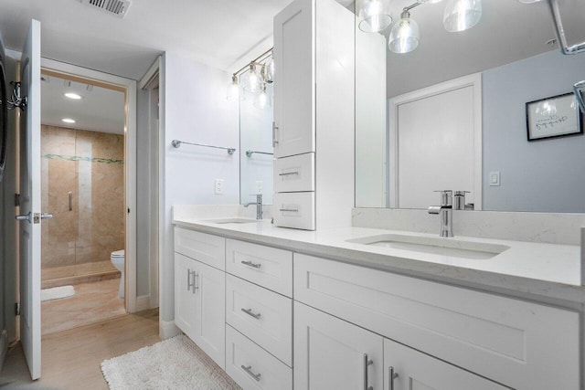 bathroom featuring hardwood / wood-style floors, vanity, toilet, and an enclosed shower