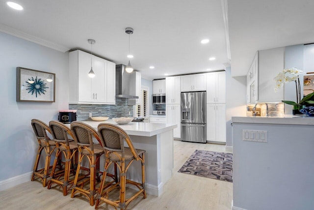 kitchen featuring white cabinetry, kitchen peninsula, light hardwood / wood-style flooring, stainless steel fridge with ice dispenser, and wall chimney range hood