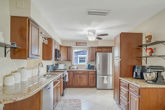 kitchen with sink, ceiling fan, light stone countertops, light tile patterned floors, and stainless steel appliances