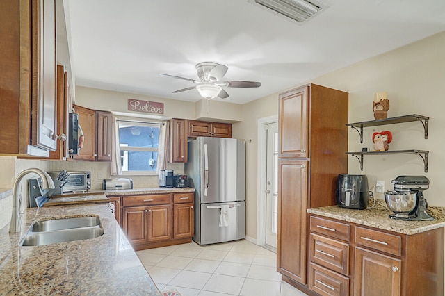 kitchen with stainless steel refrigerator, light stone countertops, sink, ceiling fan, and tasteful backsplash