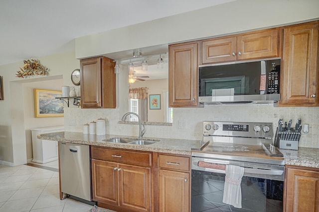 kitchen featuring light stone countertops, ceiling fan, sink, stainless steel appliances, and decorative backsplash