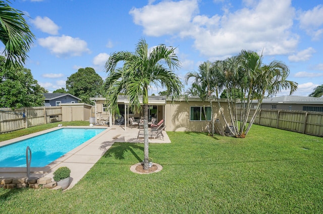 view of swimming pool featuring a yard, a patio, and a storage unit