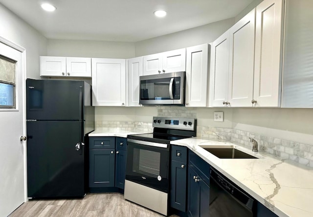 kitchen with white cabinets, light stone countertops, black appliances, and light hardwood / wood-style flooring