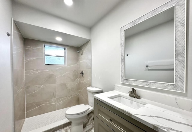 bathroom with toilet, vanity, and a tile shower