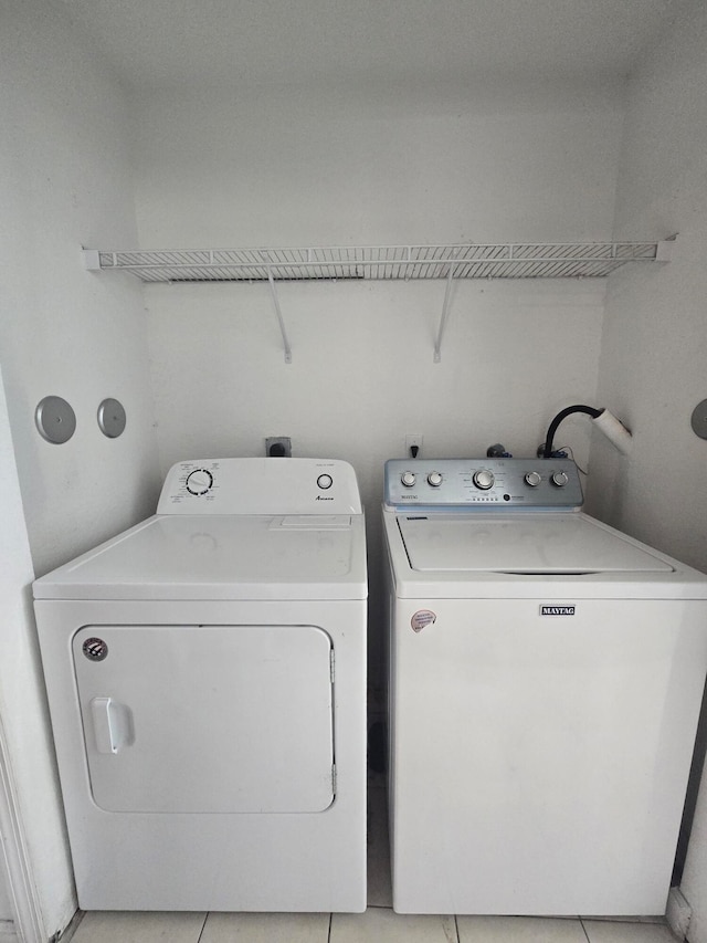 laundry area with independent washer and dryer and light tile patterned floors