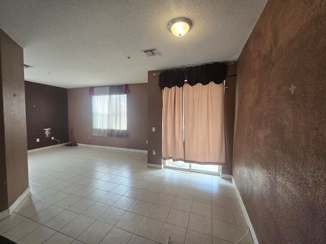 empty room featuring a textured ceiling and light tile patterned floors