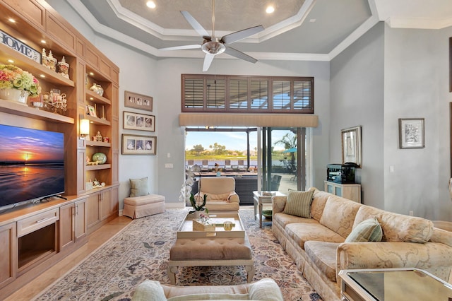 living room featuring built in shelves, a towering ceiling, light tile patterned floors, ornamental molding, and ceiling fan