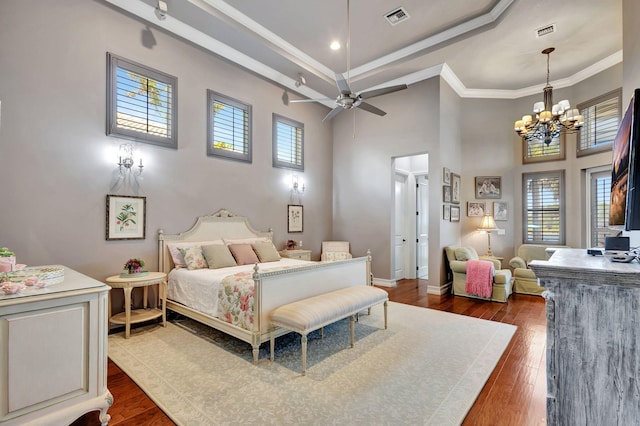 bedroom featuring ceiling fan with notable chandelier, multiple windows, dark hardwood / wood-style flooring, and crown molding