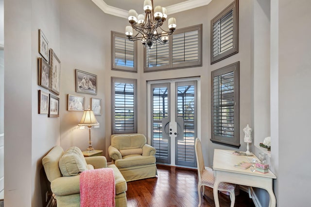 living area with a high ceiling, a chandelier, dark hardwood / wood-style floors, and crown molding