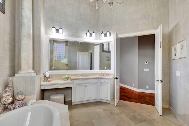 bathroom with a bath, vanity, a notable chandelier, ornate columns, and hardwood / wood-style flooring